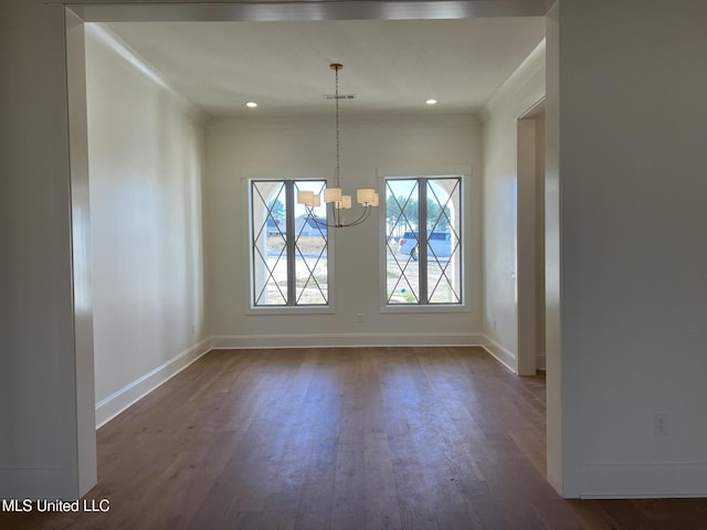 unfurnished dining area featuring dark hardwood / wood-style flooring, ornamental molding, and a chandelier