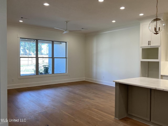 interior space featuring dark wood-type flooring, ceiling fan, and ornamental molding