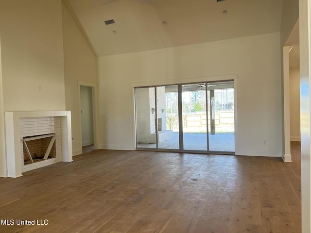 unfurnished living room featuring wood-type flooring, high vaulted ceiling, and a brick fireplace