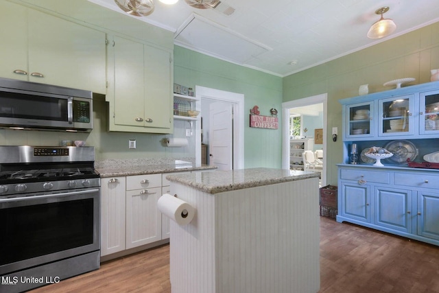 kitchen featuring hardwood / wood-style flooring, a kitchen island, ornamental molding, and appliances with stainless steel finishes