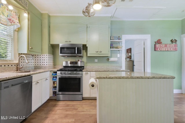 kitchen featuring sink, light hardwood / wood-style flooring, ornamental molding, white cabinetry, and stainless steel appliances