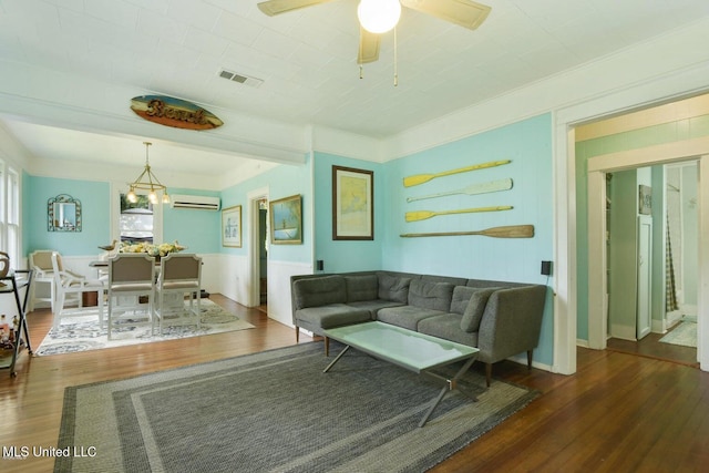 living room featuring ornamental molding, ceiling fan with notable chandelier, an AC wall unit, and dark wood-type flooring