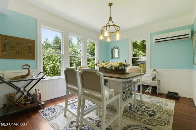 dining room featuring dark wood-type flooring, a wall unit AC, and a chandelier