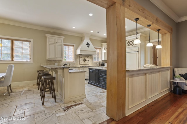 430 Johnstone Dr, Madison, MS 39110 - kitchen featuring custom range hood, a peninsula, a breakfast bar area, light stone countertops, and crown molding