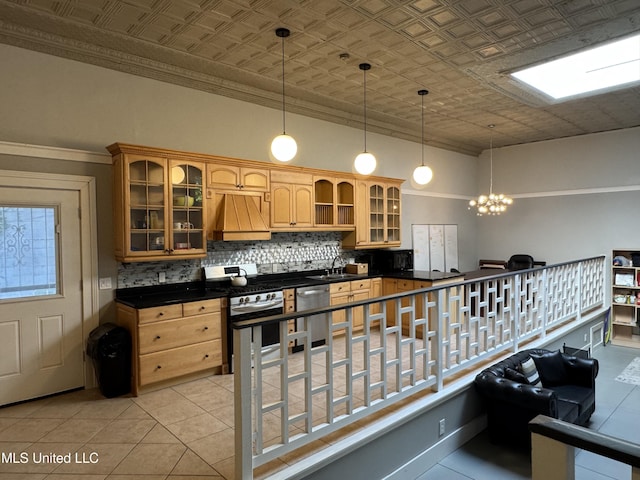 kitchen with hanging light fixtures, appliances with stainless steel finishes, tasteful backsplash, custom range hood, and a chandelier