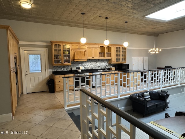 kitchen with sink, an inviting chandelier, decorative backsplash, light tile patterned flooring, and custom exhaust hood