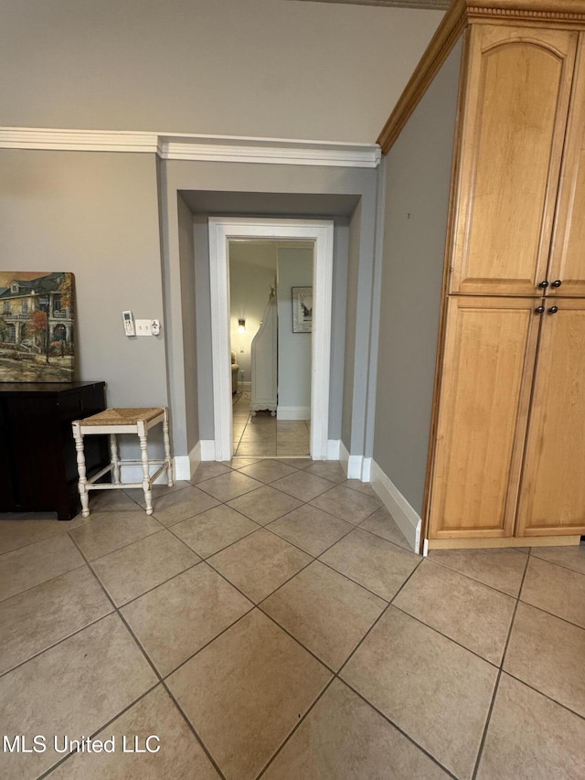 hallway with light tile patterned floors and crown molding