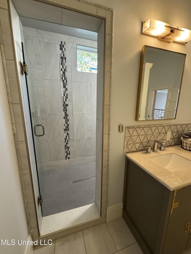 bathroom with vanity, tasteful backsplash, tile patterned floors, and walk in shower