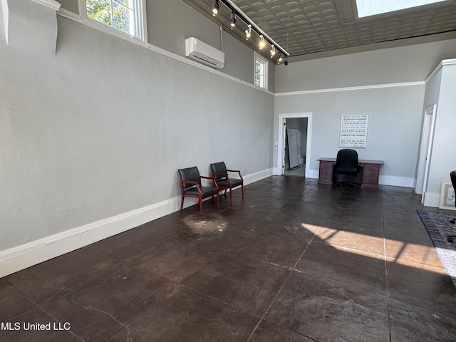 interior space with an AC wall unit, track lighting, and a high ceiling