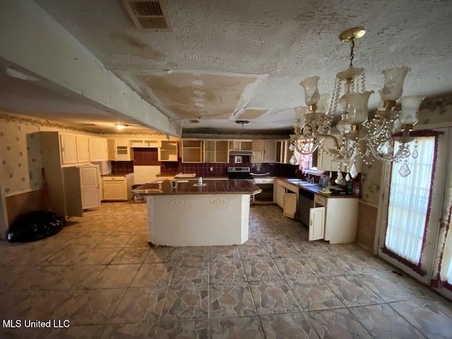 kitchen featuring visible vents, dishwasher, dark countertops, a kitchen island, and a textured ceiling