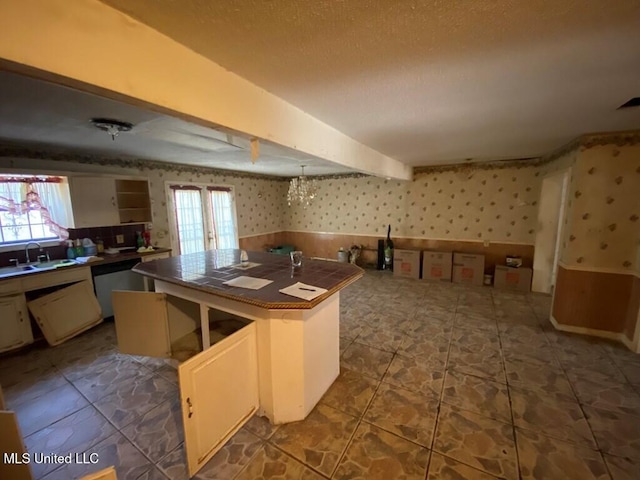 kitchen with dishwasher, a kitchen island, a sink, and wallpapered walls