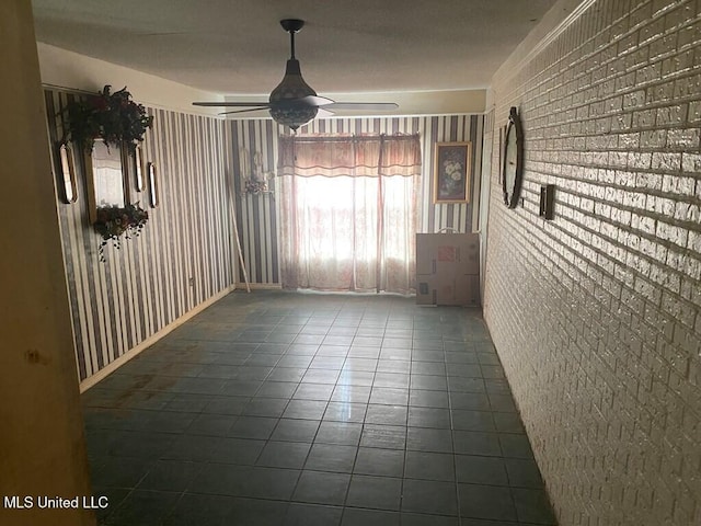 unfurnished dining area with ceiling fan, brick wall, and tile patterned floors