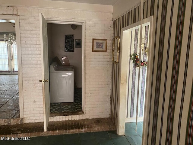 interior space with washer / clothes dryer, brick wall, and tile patterned floors