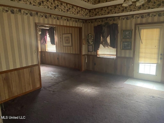 spare room featuring carpet floors, wainscoting, and wallpapered walls