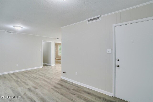 unfurnished room with crown molding, a textured ceiling, and light wood-type flooring