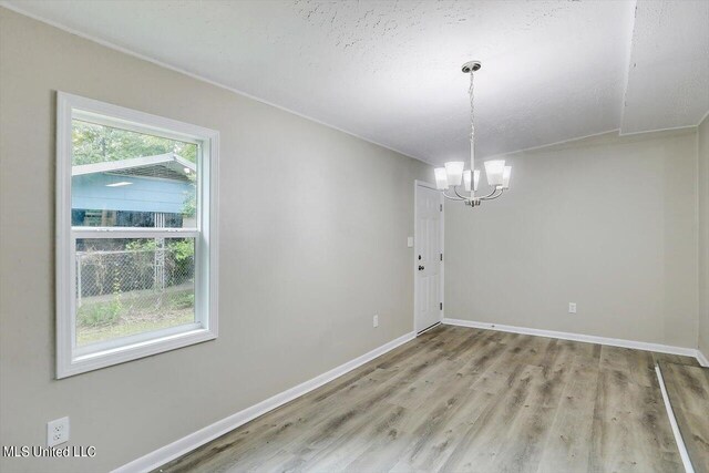 unfurnished dining area featuring a chandelier, wood-type flooring, and a textured ceiling