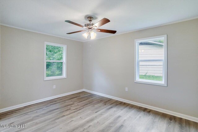 spare room featuring a wealth of natural light, ornamental molding, light hardwood / wood-style floors, and ceiling fan