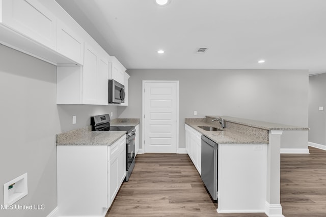 133 Maria St, Poplarville, MS 39470 - kitchen with appliances with stainless steel finishes, a sink, a peninsula, light wood-style floors, and white cabinetry