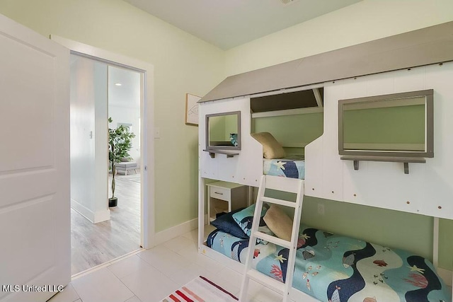 bedroom featuring light tile patterned floors and baseboards