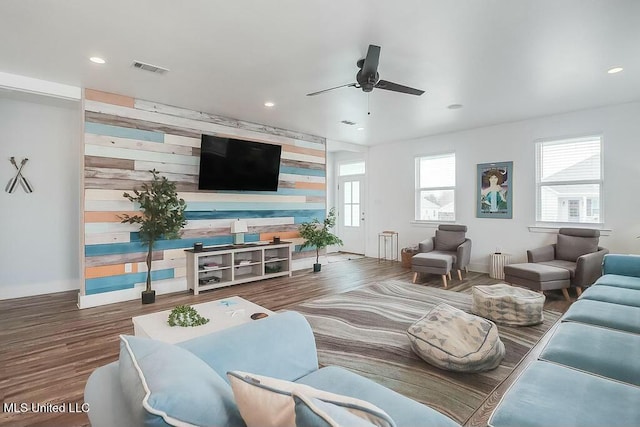 living room with an accent wall, recessed lighting, a ceiling fan, and wood finished floors