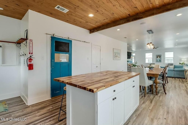 kitchen with beam ceiling, visible vents, wooden counters, white cabinetry, and light wood-type flooring