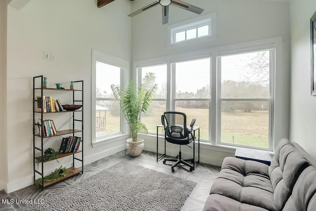 office space featuring a wealth of natural light, ceiling fan, and baseboards