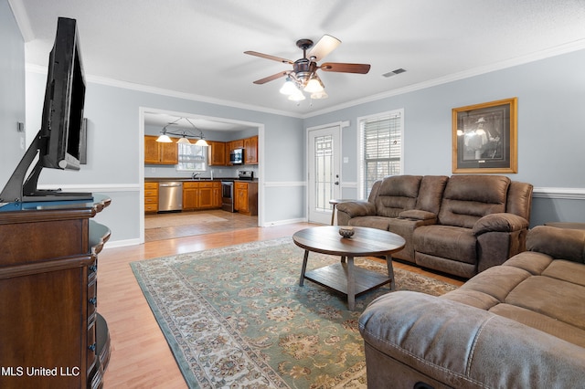 living room with crown molding, ceiling fan, visible vents, and light wood-style floors