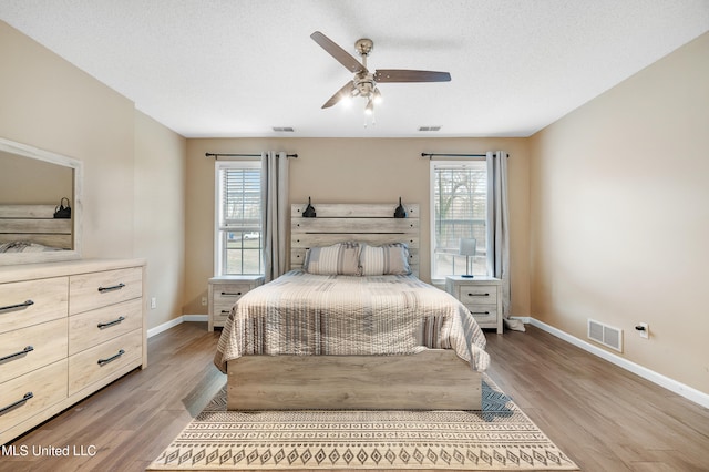 bedroom with multiple windows, visible vents, and wood finished floors