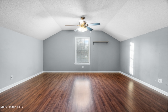 additional living space featuring lofted ceiling, a textured ceiling, baseboards, and wood finished floors