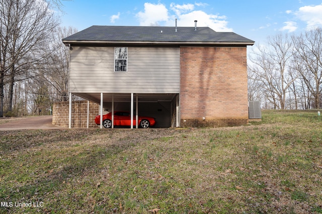 back of house with a carport, brick siding, and a lawn