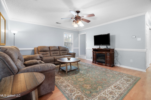 living room with visible vents, crown molding, and wood finished floors