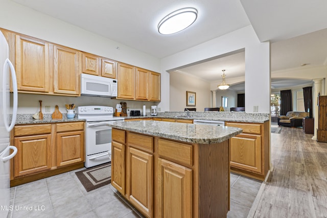 kitchen featuring kitchen peninsula, decorative columns, a kitchen island, light wood-type flooring, and white appliances