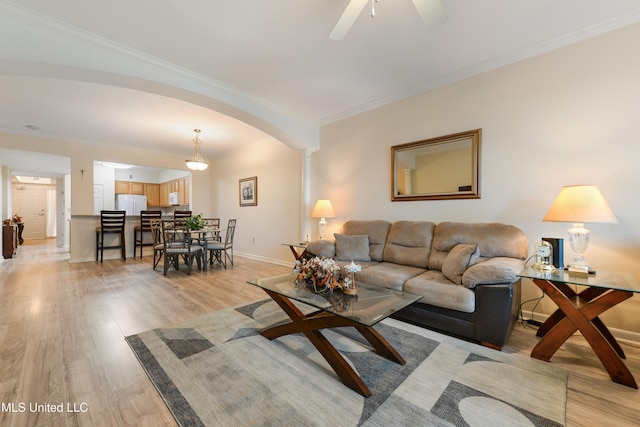 living room with ceiling fan, ornate columns, light hardwood / wood-style flooring, and ornamental molding