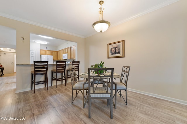 dining room with light wood-type flooring and crown molding