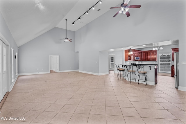 unfurnished living room with light tile patterned floors, high vaulted ceiling, and ceiling fan