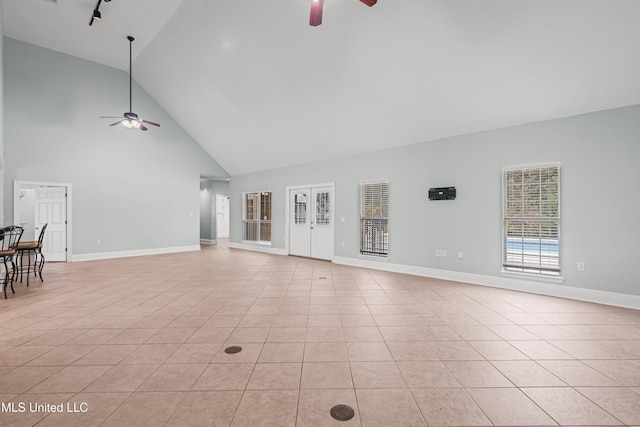 unfurnished living room with light tile patterned floors, high vaulted ceiling, and ceiling fan