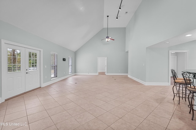 unfurnished living room with high vaulted ceiling, track lighting, french doors, ceiling fan, and light tile patterned flooring