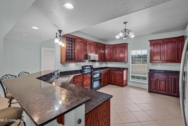 kitchen featuring kitchen peninsula, pendant lighting, black range with electric cooktop, and a breakfast bar area