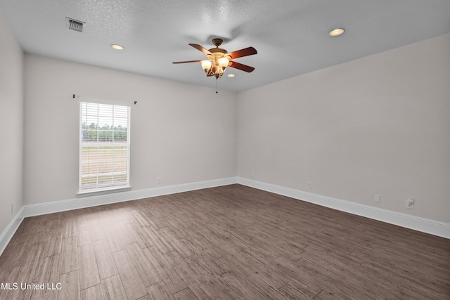 empty room with a textured ceiling, ceiling fan, and dark hardwood / wood-style floors