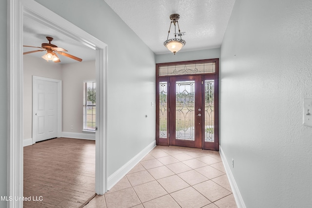 tiled foyer entrance featuring ceiling fan and a textured ceiling