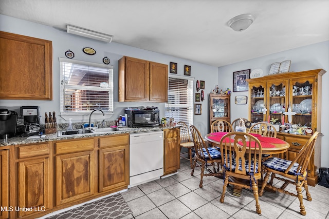 kitchen with light stone countertops, light tile patterned floors, white dishwasher, and sink