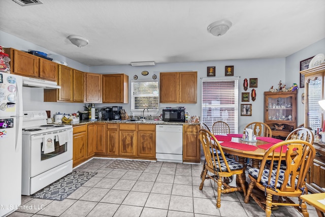 kitchen with light stone counters, sink, light tile patterned flooring, and white appliances