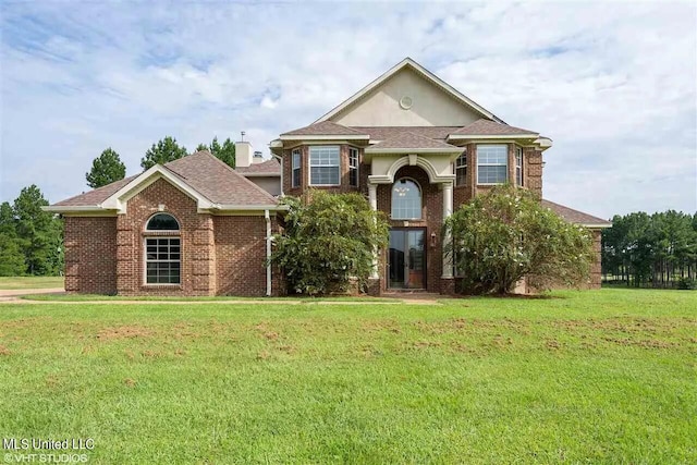 view of front facade featuring roof with shingles, a front lawn, and brick siding