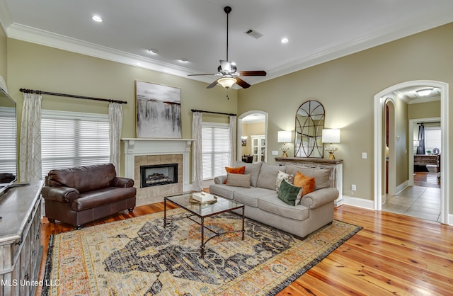 718 Tortoise Rdg, Brandon, MS 39047 - living area featuring arched walkways, crown molding, a ceiling fan, hardwood / wood-style flooring, and a tiled fireplace