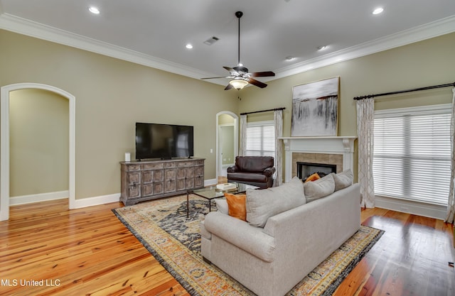 718 Tortoise Rdg, Brandon, MS 39047 - living room with arched walkways, a tiled fireplace, crown molding, wood finished floors, and ceiling fan