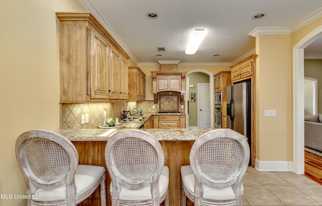 718 Tortoise Rdg, Brandon, MS 39047 - kitchen with stainless steel appliances, arched walkways, a sink, a peninsula, and light stone countertops
