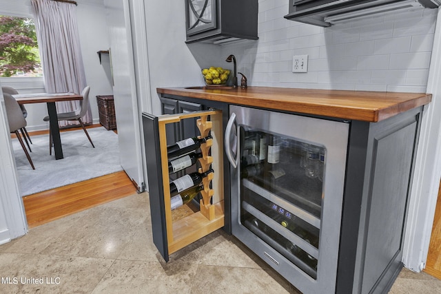 details with sink, butcher block counters, backsplash, light hardwood / wood-style floors, and wine cooler