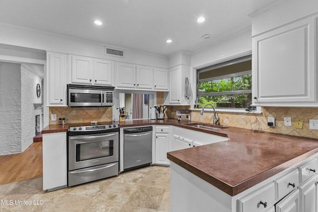 kitchen featuring white cabinetry, stainless steel appliances, ornamental molding, and sink