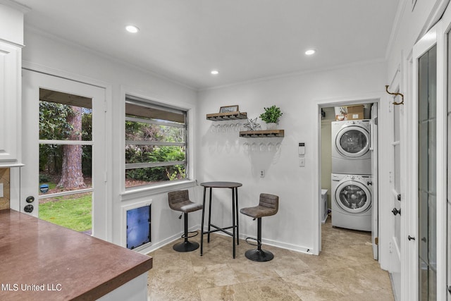 laundry area featuring crown molding and stacked washer and dryer