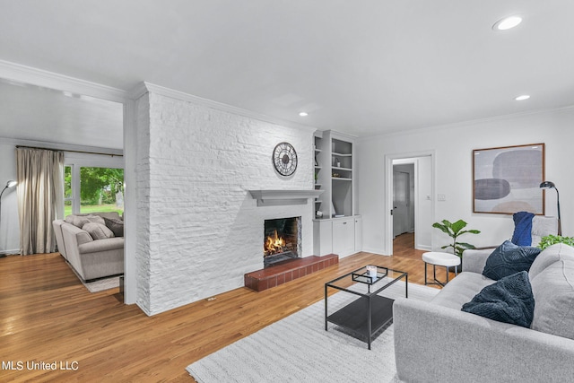 living room with crown molding, hardwood / wood-style floors, a fireplace, and built in shelves